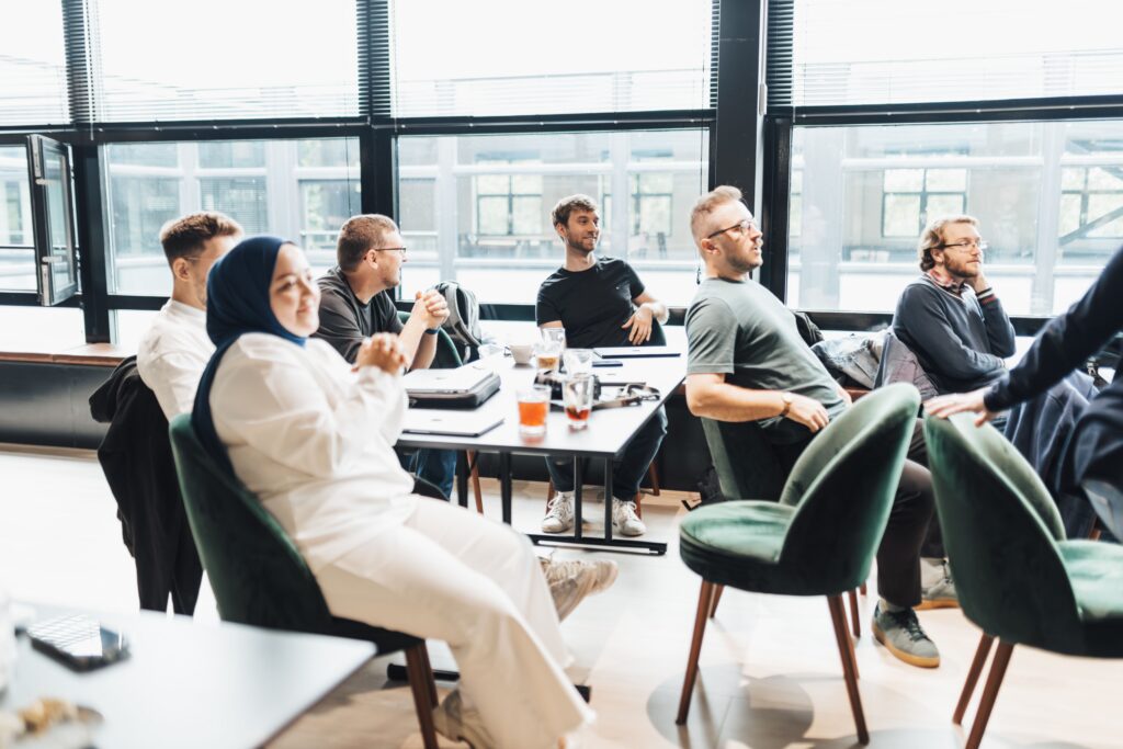 Deelnemers luisteren naar een gesprek in een lichte ontmoetingsruimte