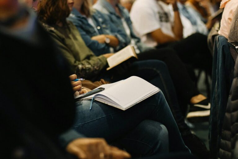 Publiek dat aandachtig luistert en notities neemt tijdens een sessie